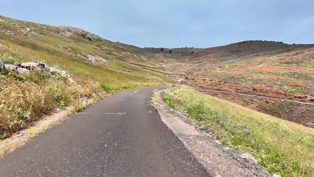 A beautiful mountain road surrounded by lush greenery and vibrant red clay landscape photo