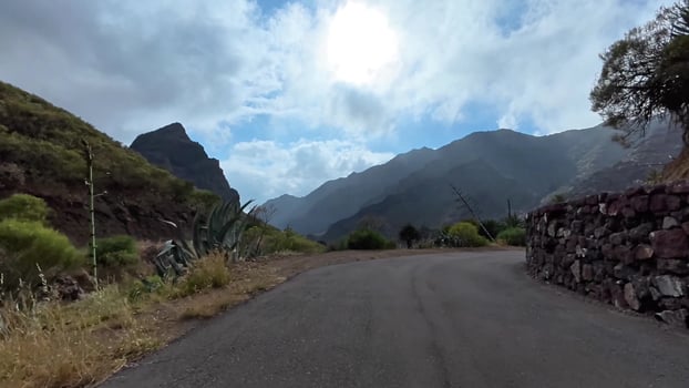A beautiful and scenic mountain road adorned with lush greenery and a dramatic sky above photo