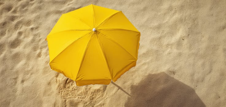 The vibrant yellow umbrella resting on golden sand at the beach. photo