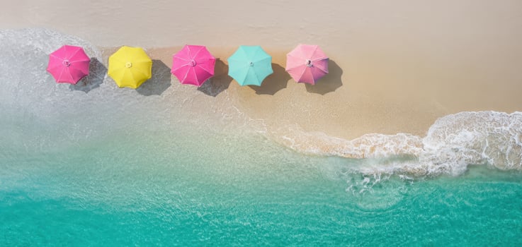 The colorful beach umbrellas lined on the sandy shore facing the ocean waves. photo