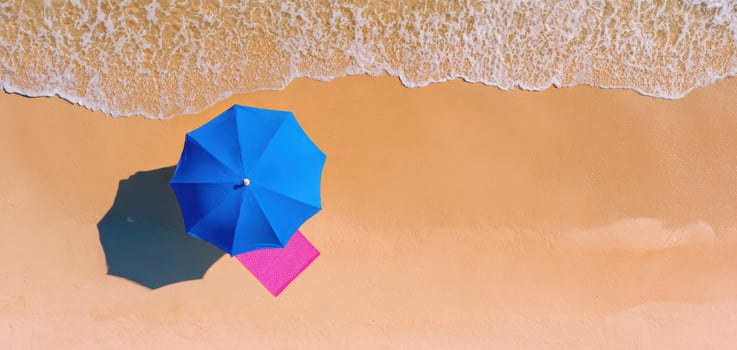 The colorful beach umbrellas casting shadows on golden sand above the ocean. photo