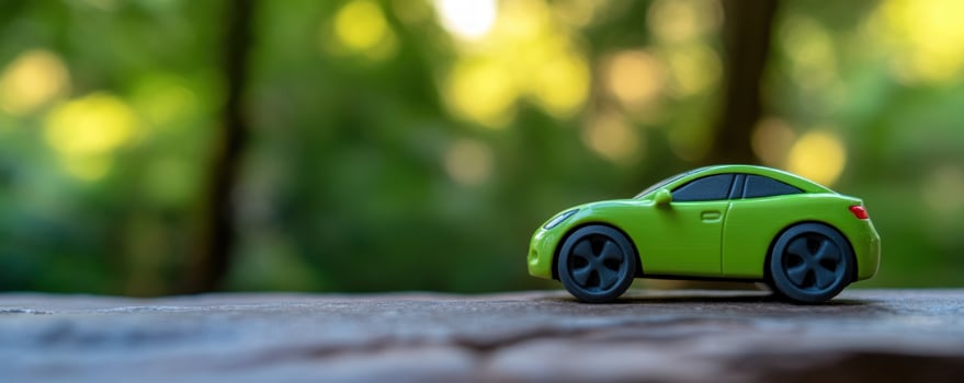 EcoFriendly Journey A Miniature Green Car on a Stone Surface with a Lush Green Background photo