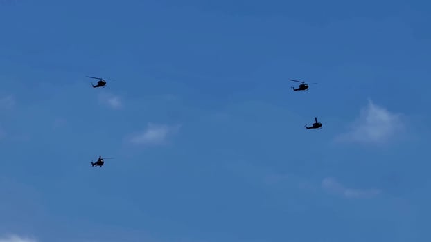 An Impressive Formation of Helicopters Flying Gracefully in the Clear Blue Sky Above photo
