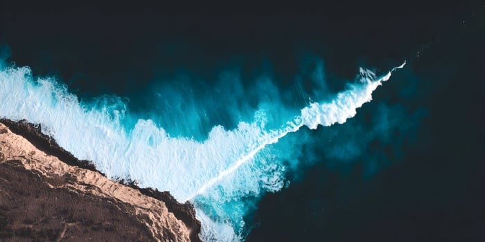Ocean waves crashing against a rocky cliff from above photo