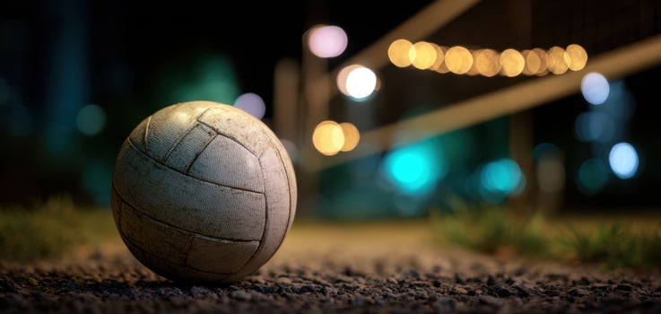 The volleyball resting on the ground illuminated by evening lights. photo