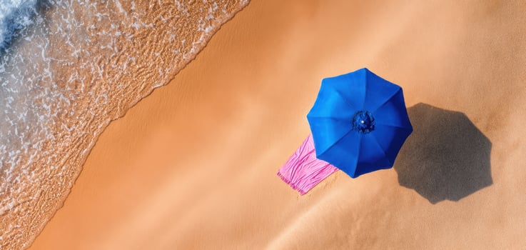 The Blue Umbrella on the Sandy Beach with Gentle Ocean Waves photo