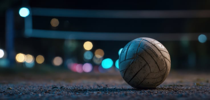 The volleyball rests on the sandy court under the night lights. photo