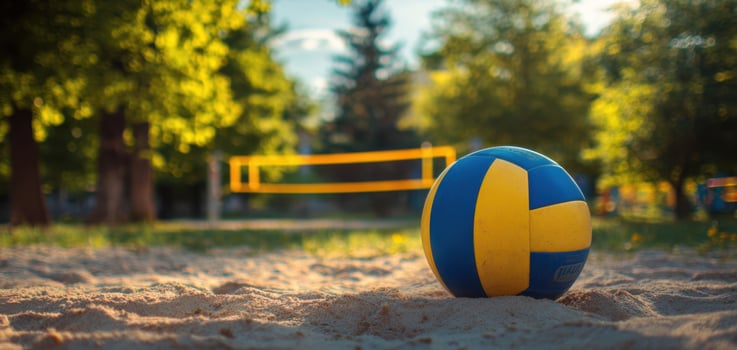 The colorful volleyball resting on sand near a beach court in sunlight. photo
