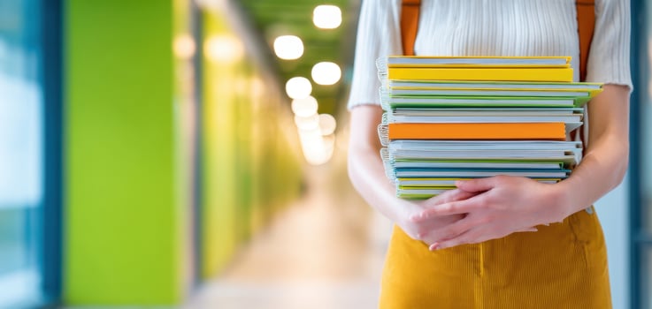 The student holding a stack of colorful books in a vibrant educational setting. photo