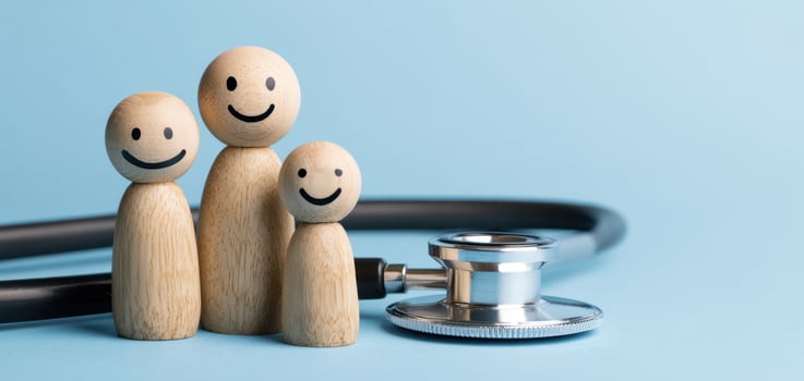 The wooden figures of a happy family beside a medical stethoscope photo