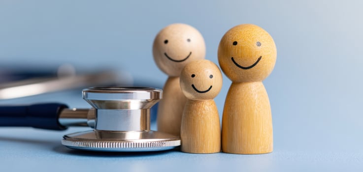 The happy family with wooden figures and a stethoscope symbolizing healthcare. photo