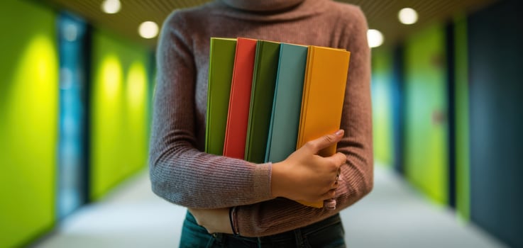 The young woman holds colorful books in a vibrant indoor corridor photo