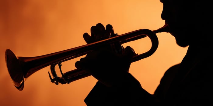 The Silhouette of a Musician Playing the Trumpet Against a Warm Background photo