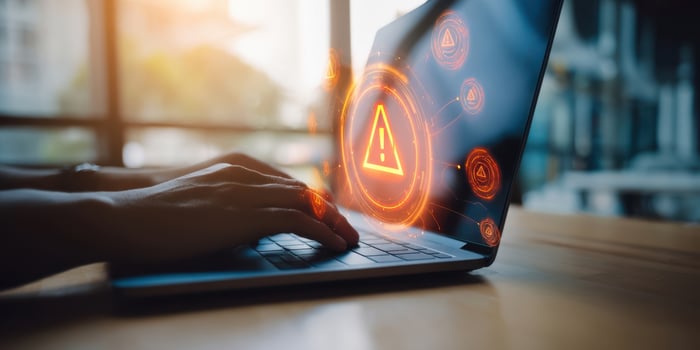 The laptop displaying warning alerts with hands typing in a modern workspace. photo