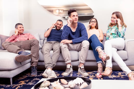 group of friends sitting on white sofa on phone at the same time photo