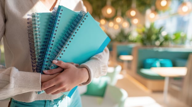 The vibrant stacked notebooks held by a student in a cozy workspace. photo