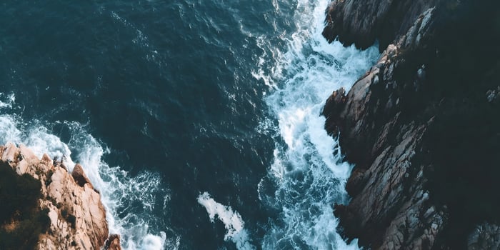 Aerial view of ocean waves crashing against rocky cliffs photo