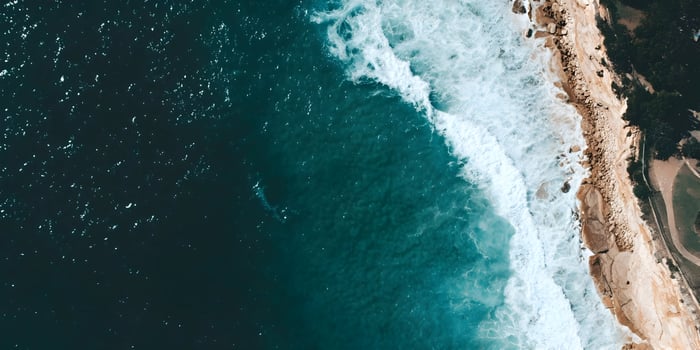 Ocean waves crashing against rocky coastline aerial view photo