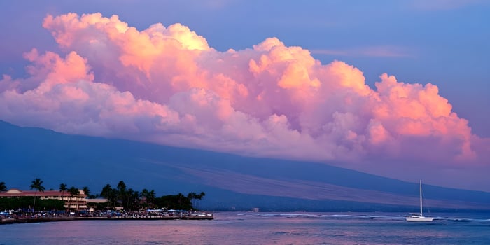 Pink and purple clouds over ocean with sailboat and mountain photo