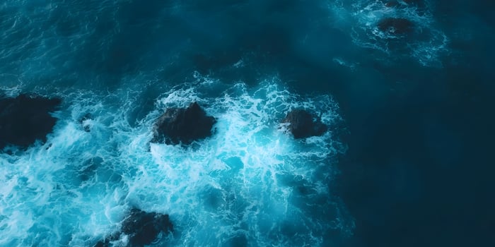 overhead view of ocean waves hitting dark rocks photo