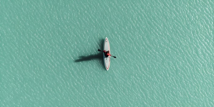 Person paddle boarding on calm teal water photo