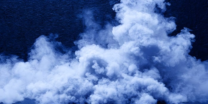 Blue smoke swirls against a dark blue background photo