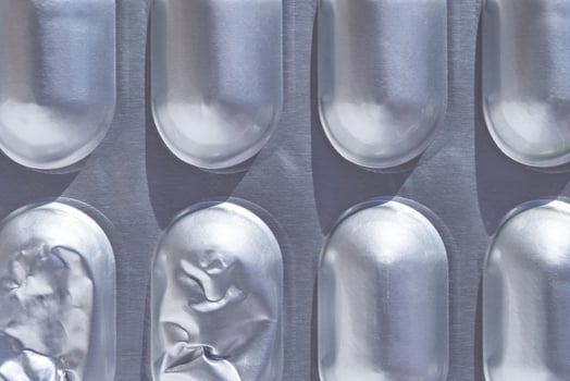 Blister pack with empty and full pill slots in silver aluminum background. photo