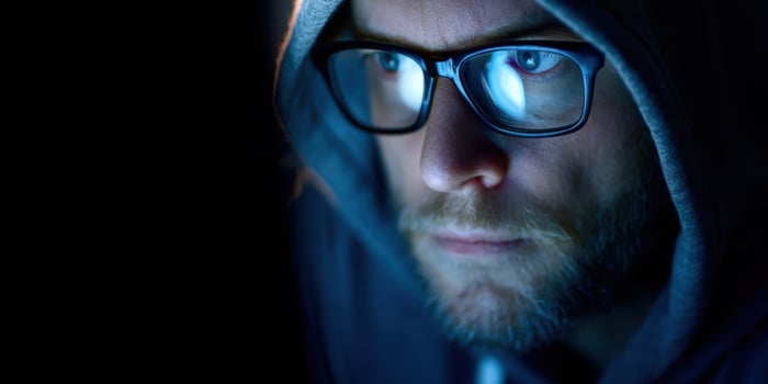 The focused man in glasses and hoodie illuminated by screen light. photo