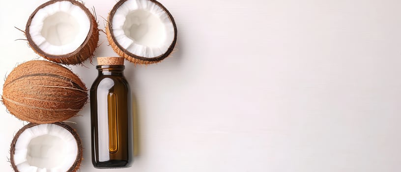 Coconut oil bottle with fresh coconut halves on white background, natural and healthy concept photo