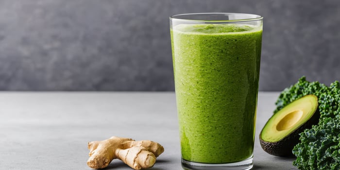 Fresh green smoothie with kale avocado and ginger root on gray surface photo