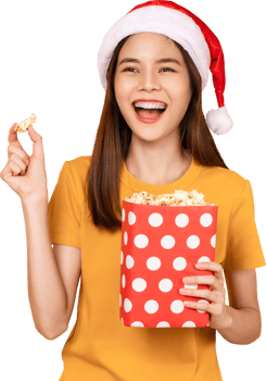woman wearing Christmas hat with holding a red bucket of popcorns while pointing front. png