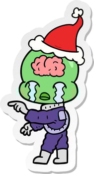 sticker cartoon of a big brain alien crying and pointing wearing santa hat vector