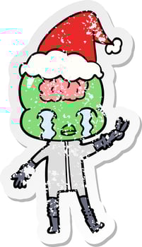 distressed sticker cartoon of a big brain alien crying and giving peace sign wearing santa hat vector