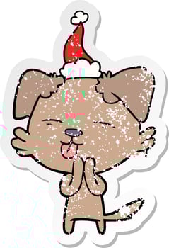 distressed sticker cartoon of a dog sticking out tongue wearing santa hat vector