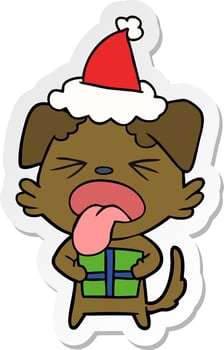 sticker cartoon of a dog with christmas present wearing santa hat vector