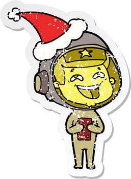 distressed sticker cartoon of a laughing astronaut wearing santa hat vector