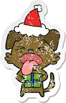 distressed sticker cartoon of a dog with christmas present wearing santa hat vector