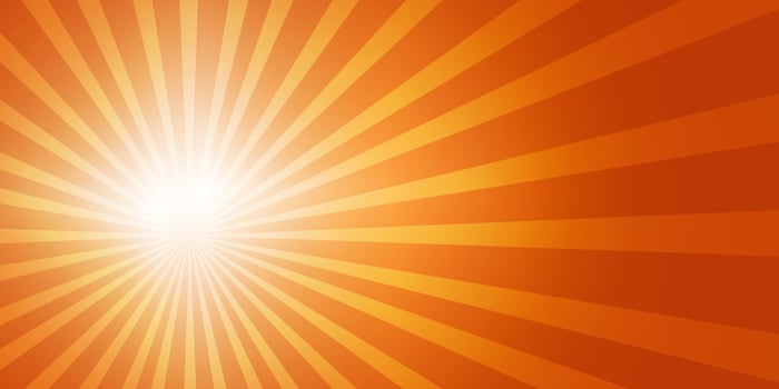 Bright sun on the left side of the sky with sun rays and lens flares in a bright orange sky. Copy space vector