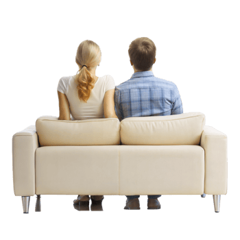 Couple sitting on beige sofa in a relaxed pose looking away png
