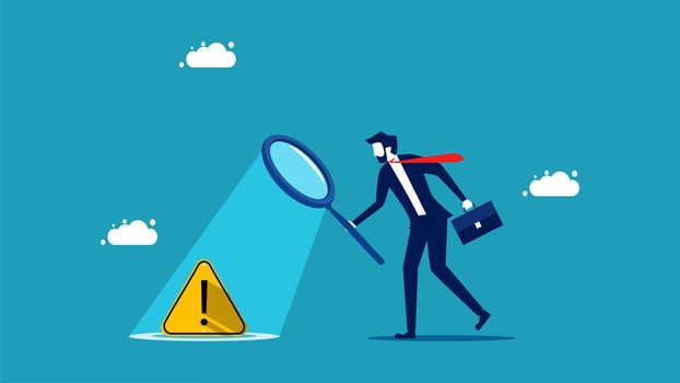 businessman with magnifying glass looking at a caution sign vector