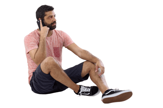 young man sitting on the floor in casual clothes talking on cell phone png