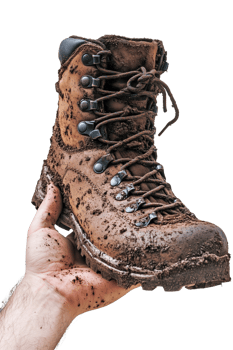Hiker holding a muddy boot with untied laces after a long day on the trail png