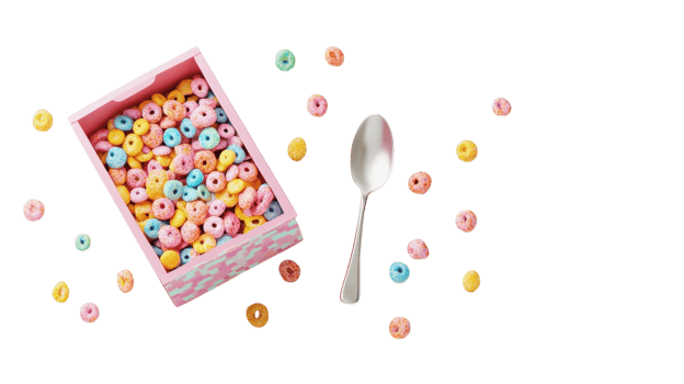Colorful cereal filling a pink box with scattered pieces and a spoon beside it on a clear background in bright daylight. png