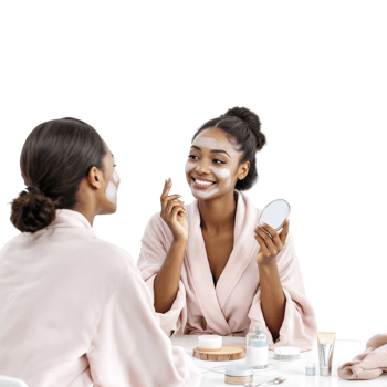 Two women in bath robes sitting at a table with a mirror and a face mask png