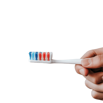 Person holds a toothbrush with colorful bristles and toothpaste in modern bathroom setting, person holding a toothbrush with toothpaste on it, Transparent background png