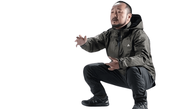 A man in a crouched position wearing outdoor gear ready for action or exercise png