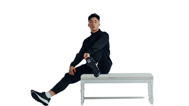 A person sitting on a white bench wearing sporty attire and sneakers showcasing a casual yet png