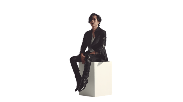 Stylish Man in Black Leather Jacket Sitting on White Cube png