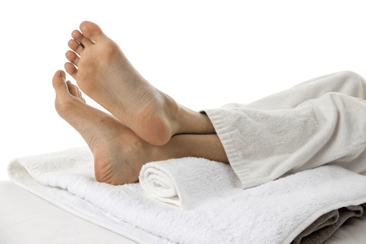 Relaxing spa treatment featuring a pair of serene feet resting on rolled towels. png