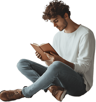 Man with curly hair sitting cross legged reading a book wearing jeans and a white long sleeved shirt png